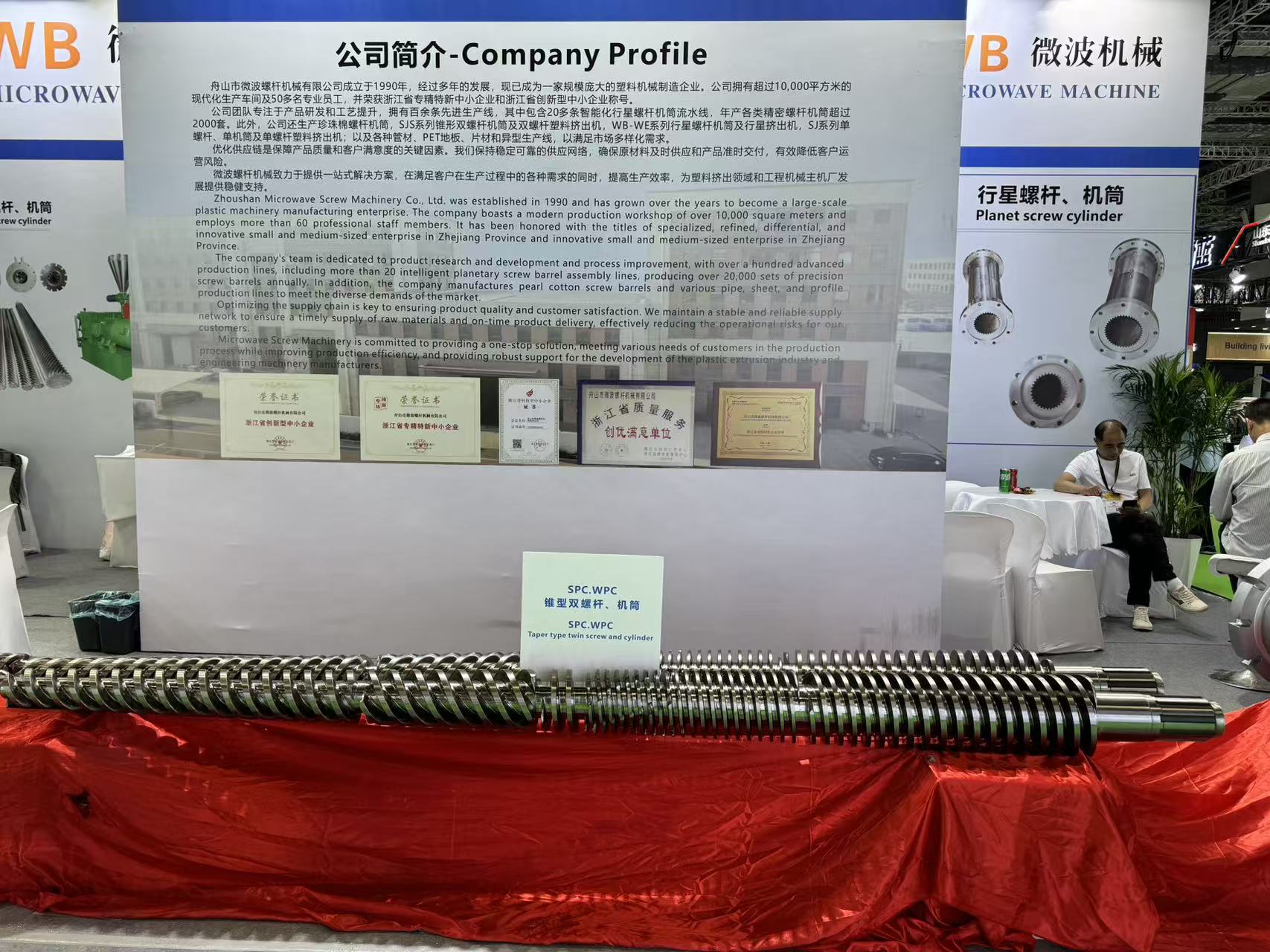 WB Microwave Machine exhibition booth company profile display at trade show, featuring SPC WPC taper twin screw and cylinder product samples and quality awards